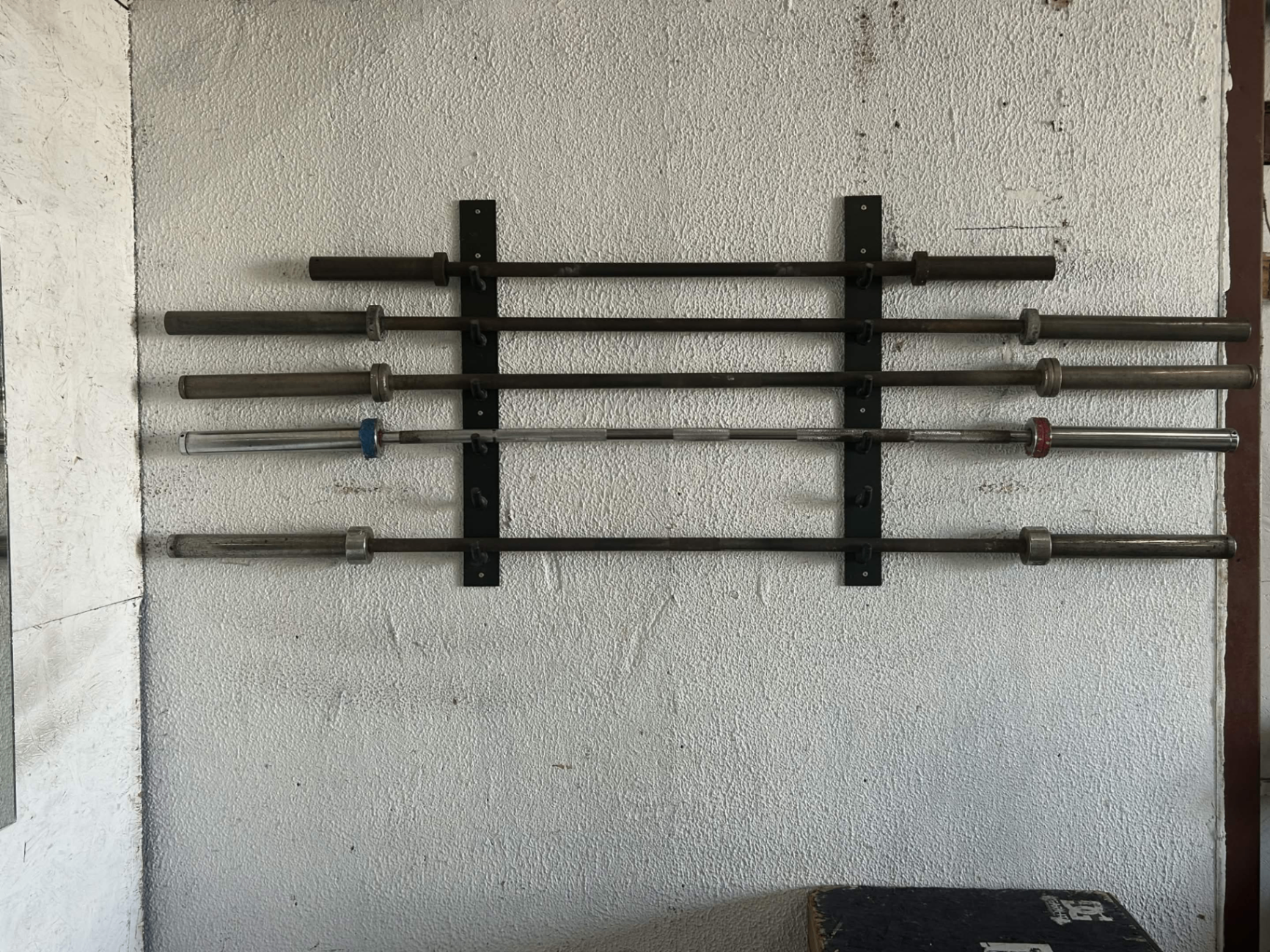 Wall-mounted barbell rack in the War Zone at Dover Gym